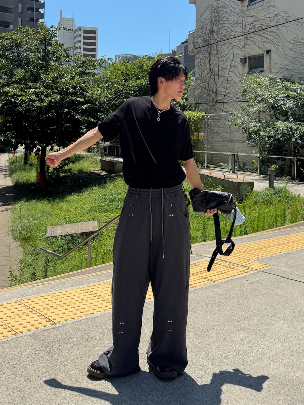 ブラック系のTシャツ/カットソー、ブラック系のショルダーバッグ、ブラウン系のローファーを着用したメンズの夏コーディネートの4枚目の写真