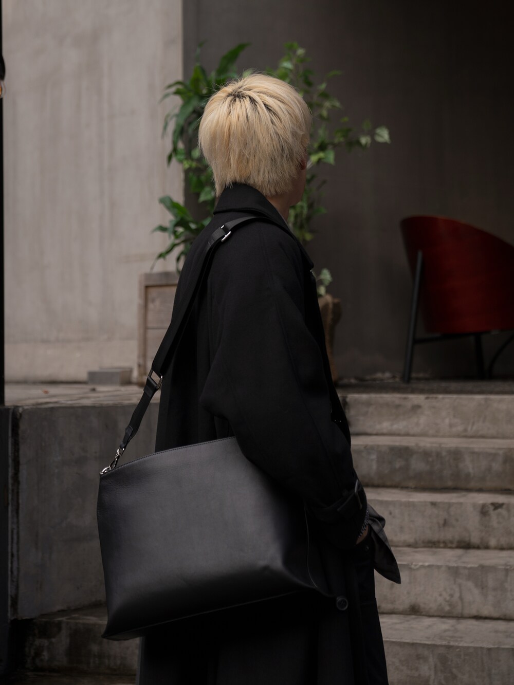 グレー系のノーカラージャケット、ブラック系のステンカラーコート、ブラック系のカーゴパンツを着用したメンズの冬コーディネートの3枚目の写真