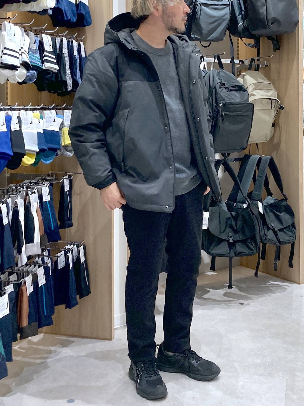 グレー系のダウンジャケット/コート、グレー系のニット/セーター、ブラック系のその他パンツを着用したメンズの秋コーディネートの4枚目の写真