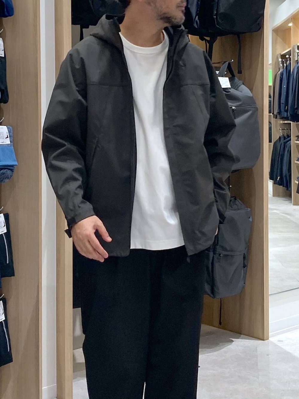 グリーン系のマウンテンパーカー、ホワイト系のTシャツ/カットソー、ブラック系のバックパック/リュックを着用したメンズの秋コーディネートの4枚目の写真