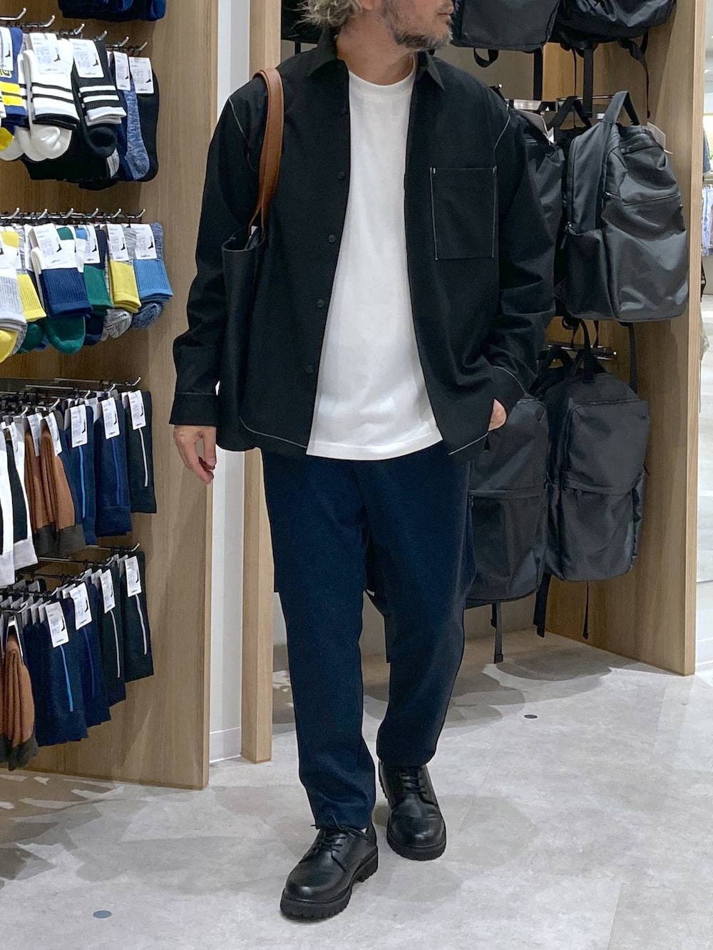 ホワイト系のTシャツ/カットソー、ブラック系のトートバッグ、ブルー系のスラックスを着用したメンズの秋コーディネートの3枚目の写真