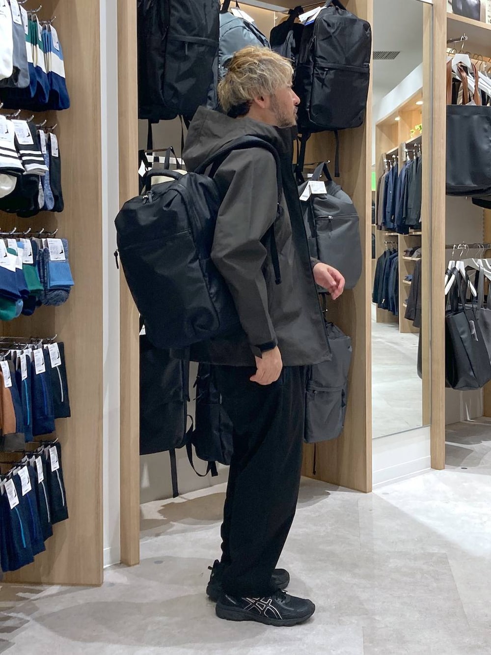 グリーン系のマウンテンパーカー、ホワイト系のTシャツ/カットソー、ブラック系のバックパック/リュックを着用したメンズの秋コーディネートの2枚目の写真