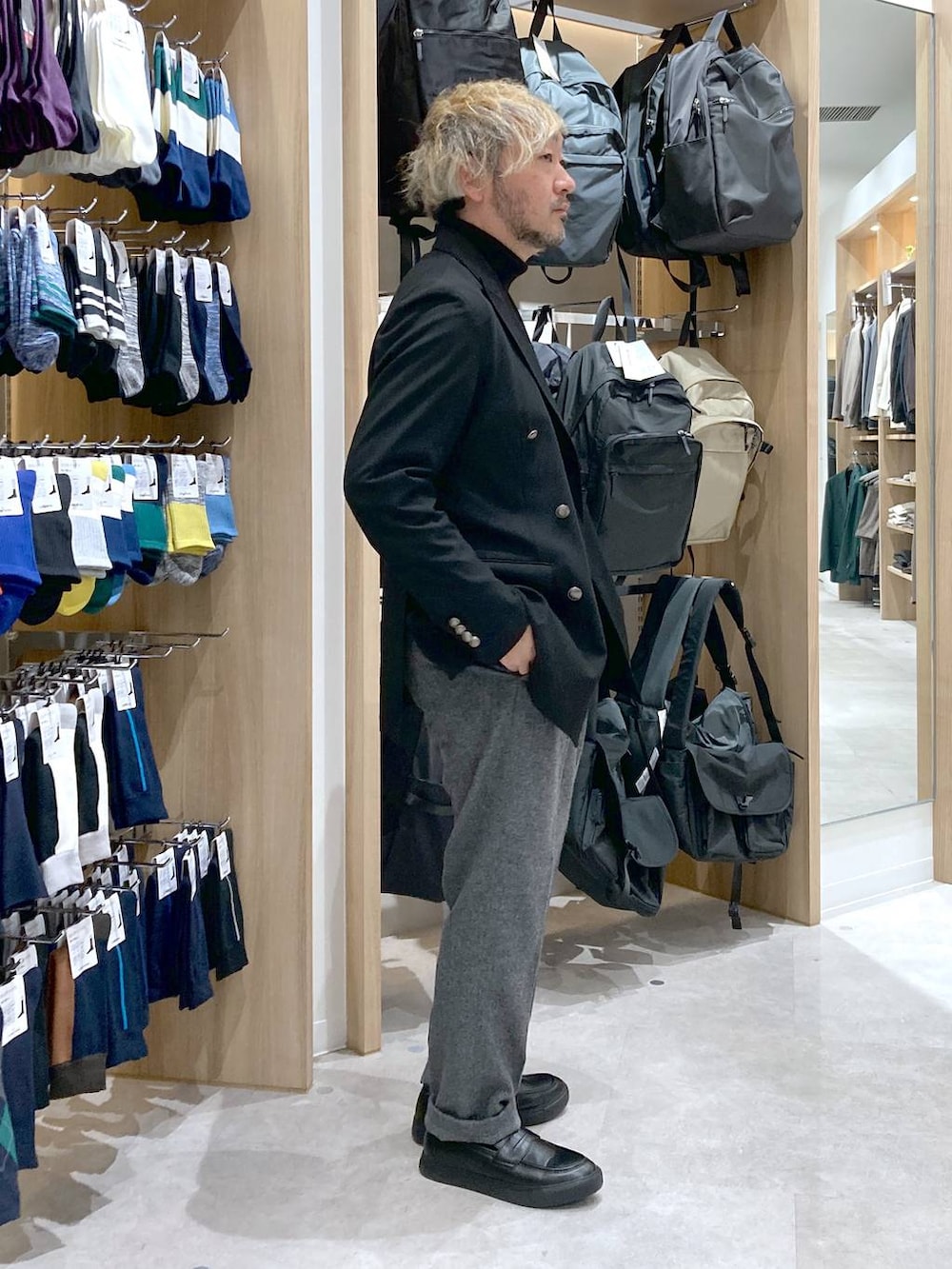 ブラック系のテーラードジャケット、グレー系のスラックス、ブラック系のニット/セーターを着用したメンズの冬コーディネートの2枚目の写真