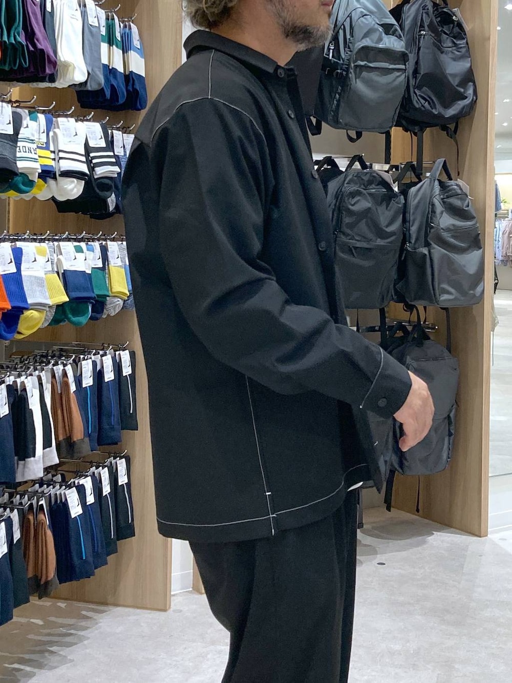 ホワイト系のTシャツ/カットソー、ブラック系のトートバッグ、ブルー系のスラックスを着用したメンズの秋コーディネートの4枚目の写真