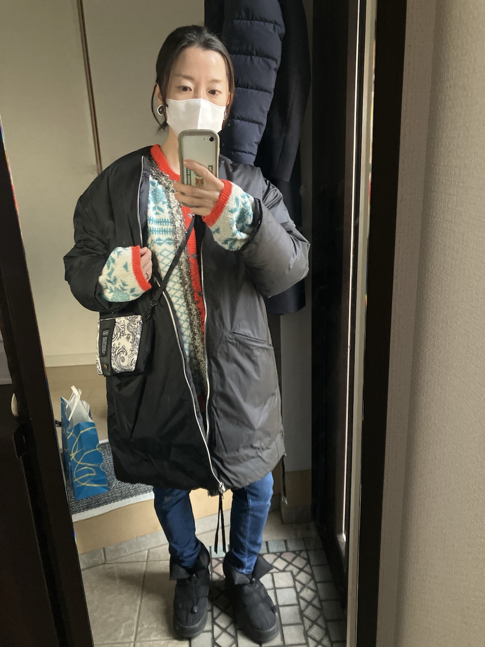 ブラック系のブルゾン、ブルー系のカーディガン/ボレロ、ブラック系のブーツを着用したレディースの冬コーディネートの2枚目の写真