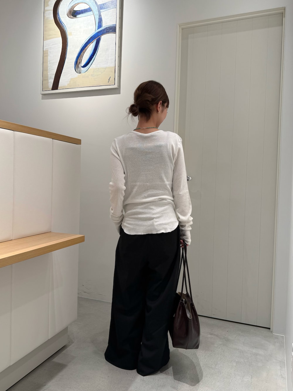 ブラウン系のトートバッグ、ホワイト系のTシャツ/カットソーを着用したレディースの夏コーディネートの3枚目の写真
