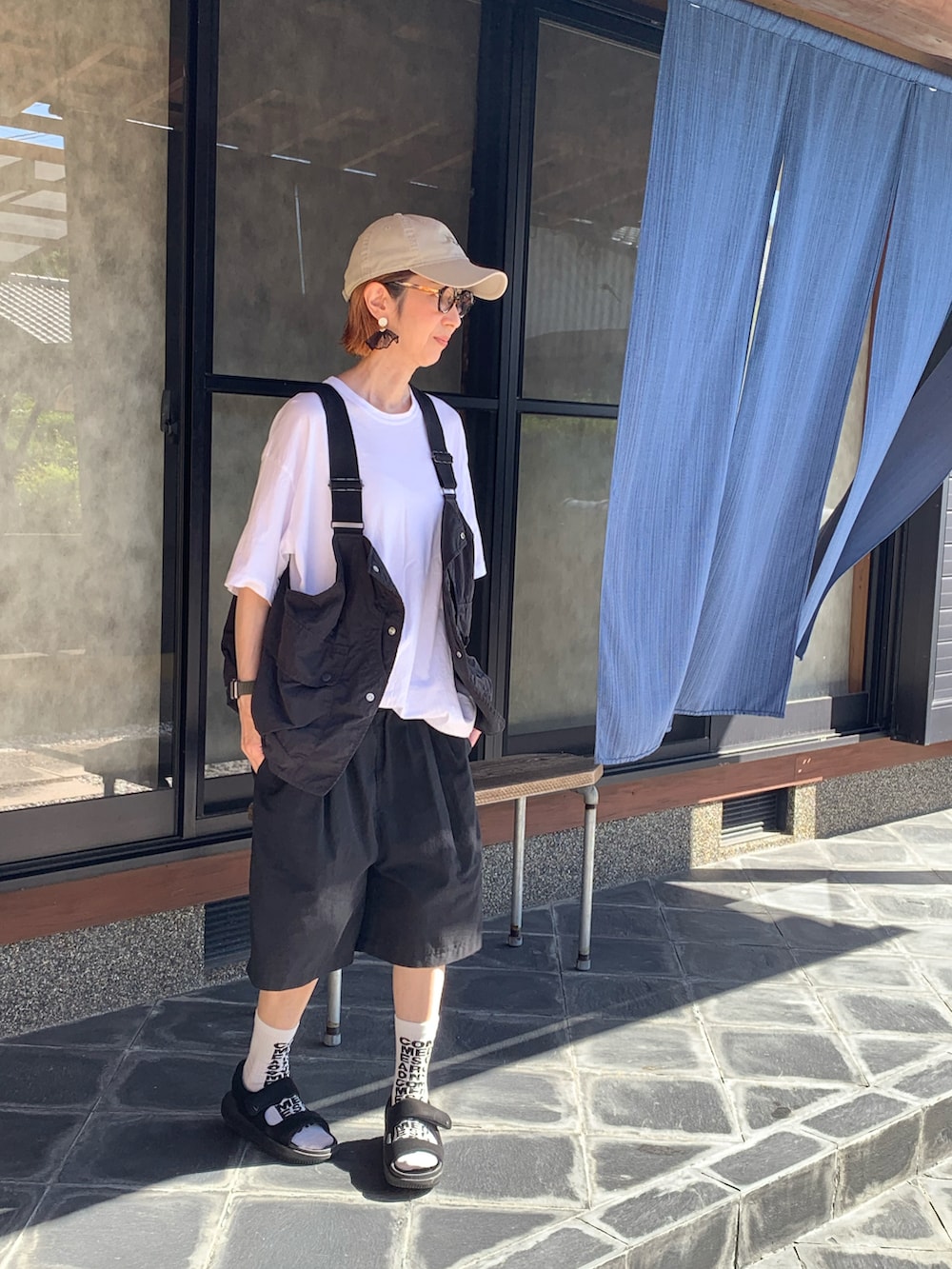 ブラック系のジャケット/アウター、ブラック系のサンダル、ベージュ系のキャップを着用したレディースの秋コーディネートの2枚目の写真