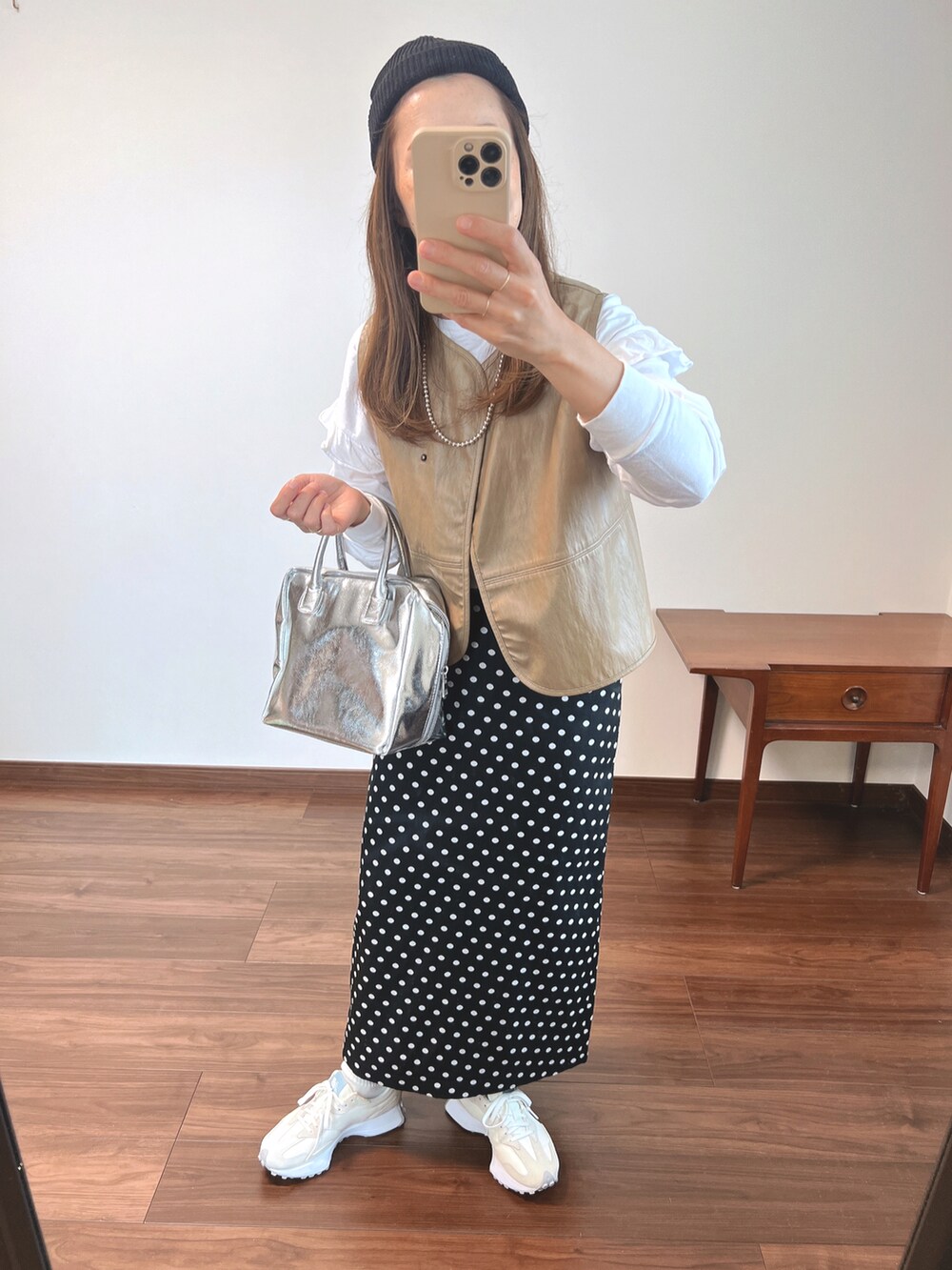 ベージュ系のベスト、ホワイト系のTシャツ/カットソー、ブラック系のスカートを着用したレディースの秋コーディネートの2枚目の写真