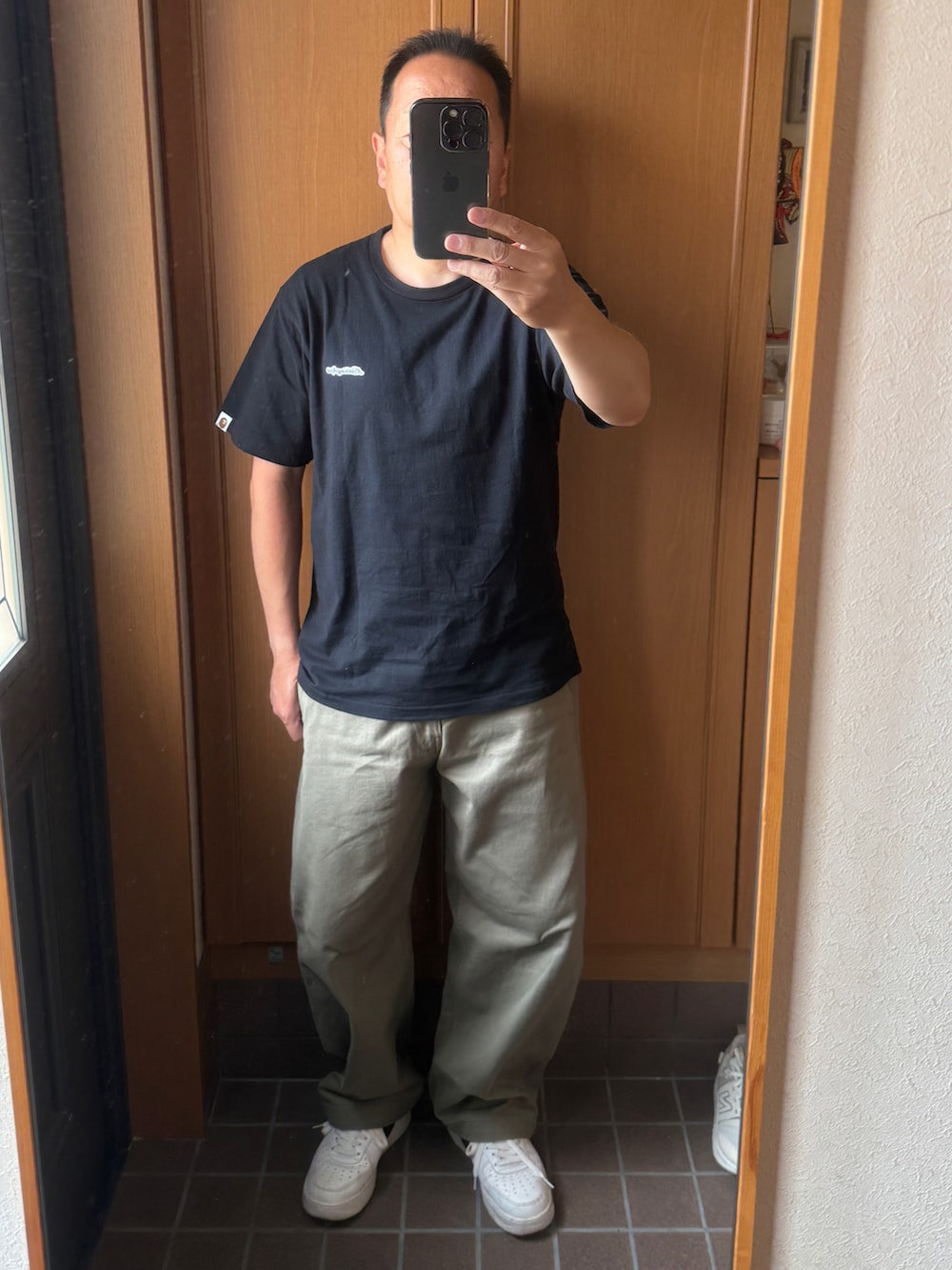 ベージュ系のカーゴパンツ、ホワイト系のスニーカー、ブラック系のTシャツ/カットソーを着用したメンズの夏コーディネートの2枚目の写真