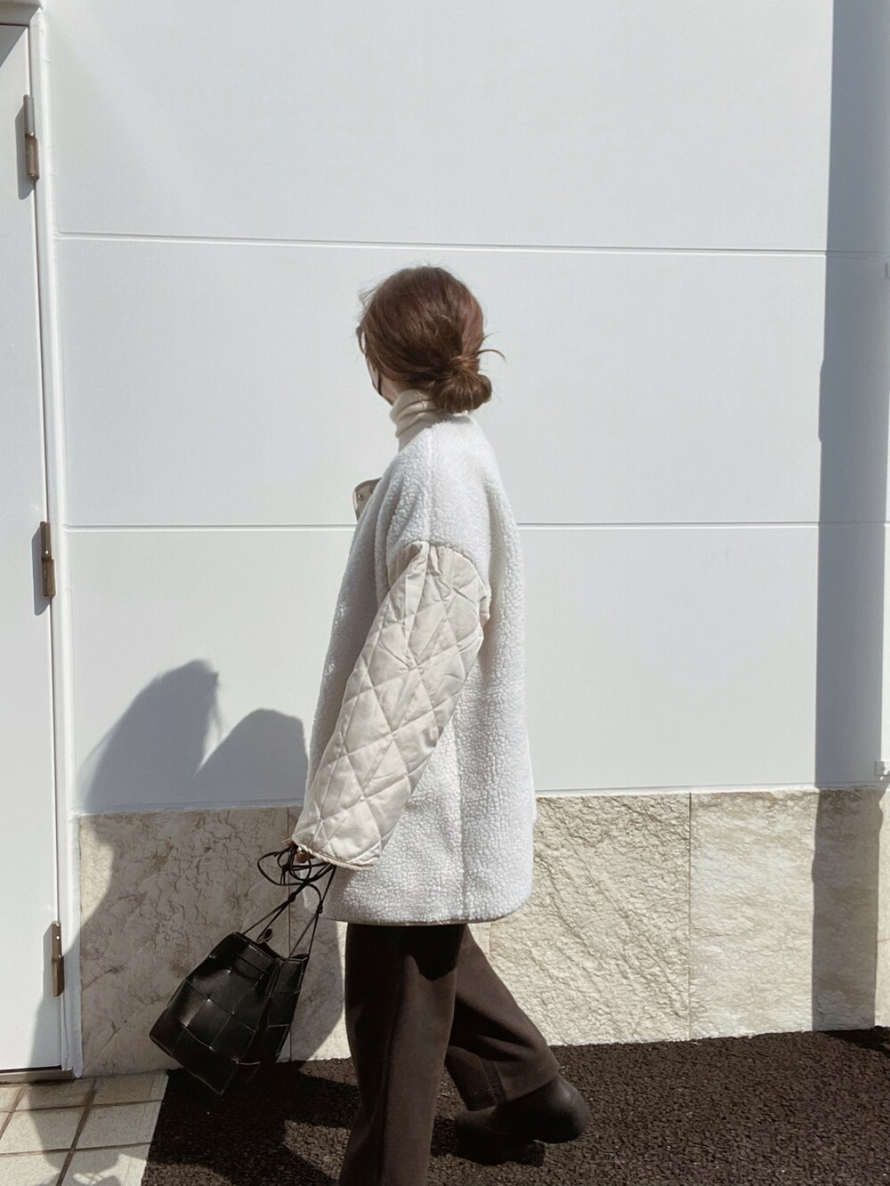 ホワイト系のノーカラージャケット、ブラック系のバッグ、ブラウン系のその他パンツを着用したレディースの秋コーディネートの3枚目の写真