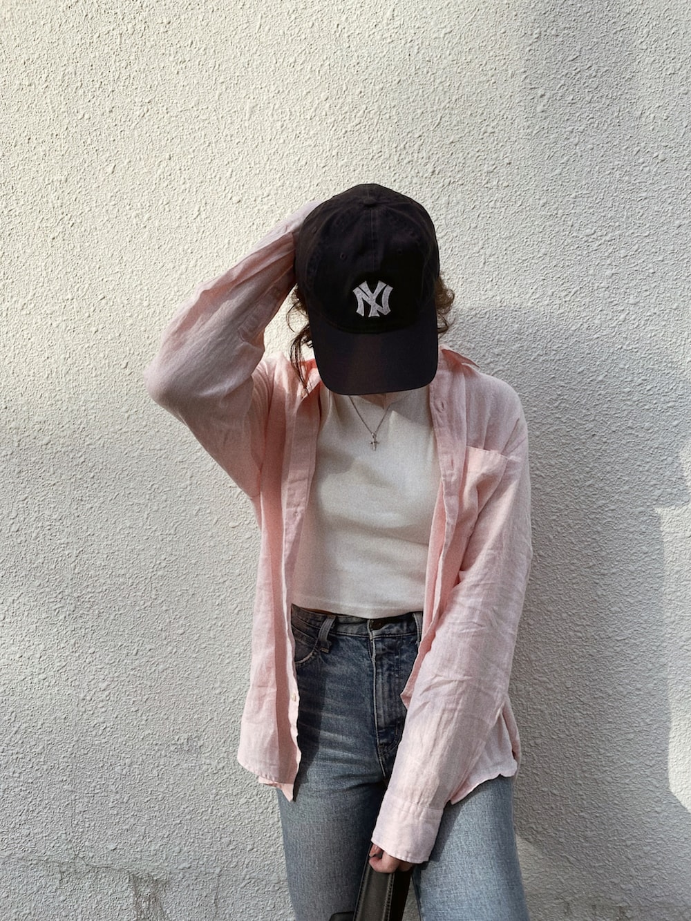 ブルー系のデニムパンツ、ホワイト系のサンダル、ピンク系のシャツ/ブラウスを着用したレディースの夏コーディネートの3枚目の写真