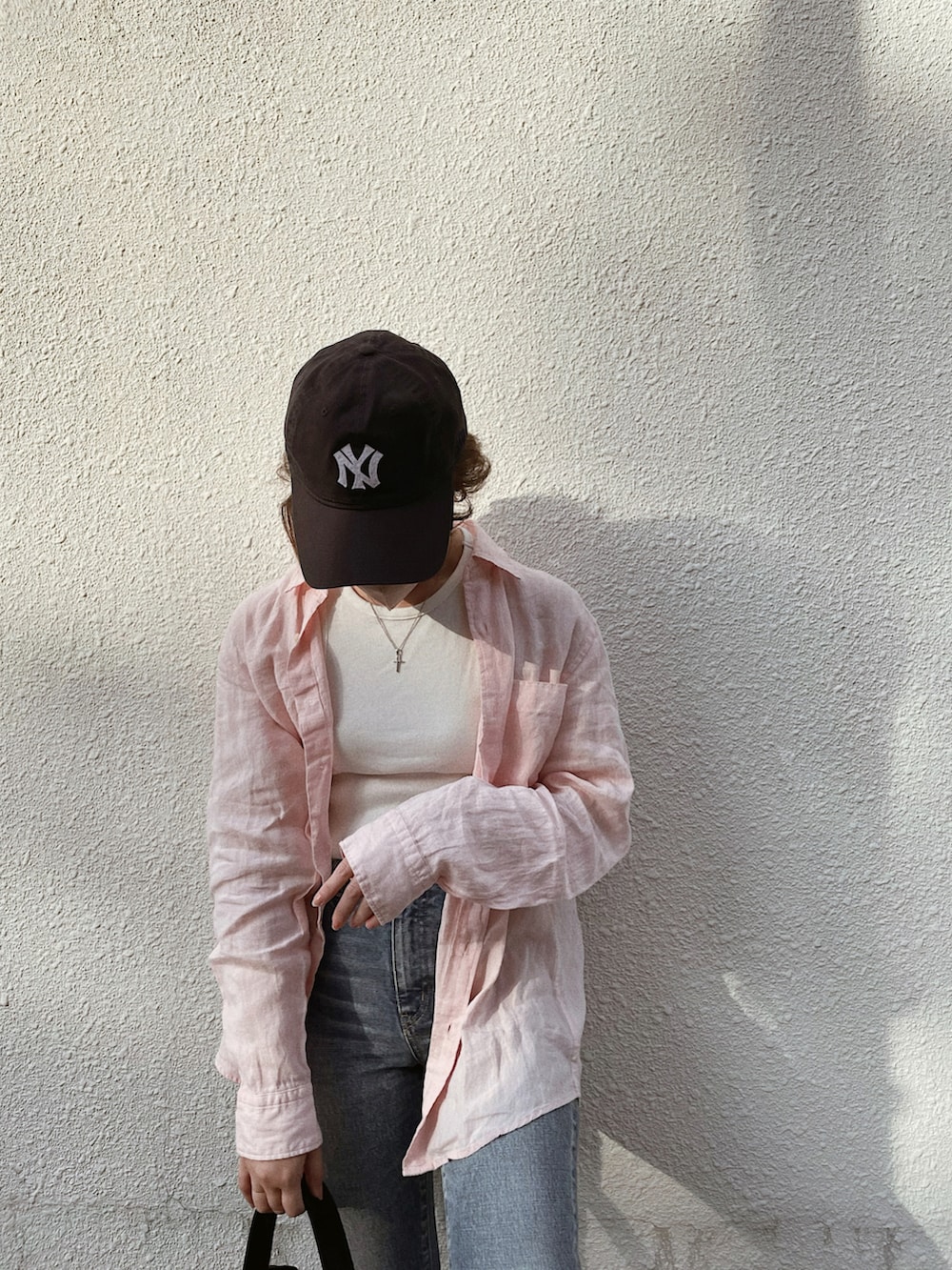 ブルー系のデニムパンツ、ホワイト系のサンダル、ピンク系のシャツ/ブラウスを着用したレディースの夏コーディネートの2枚目の写真