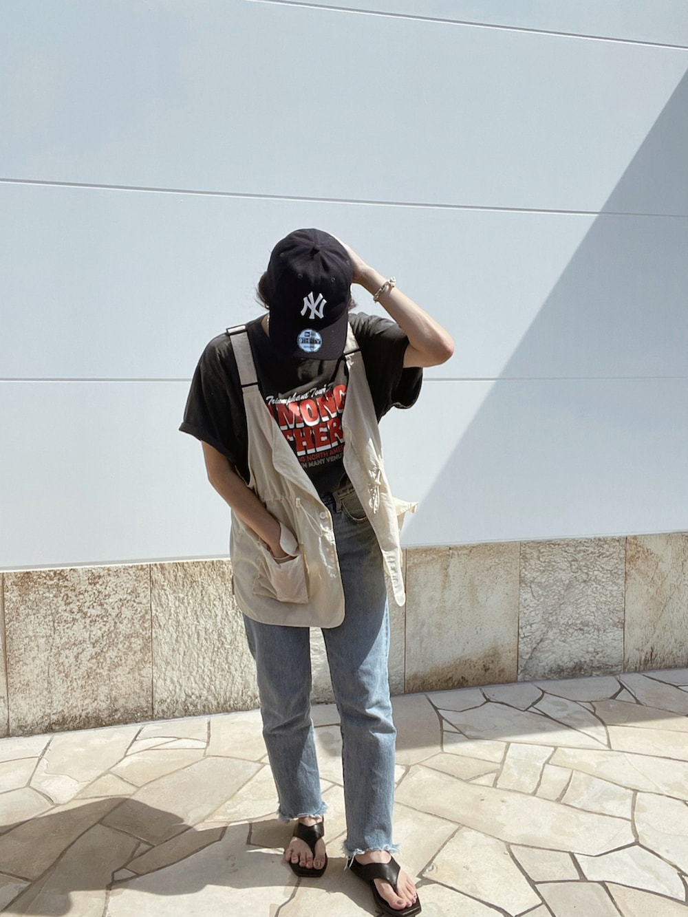グレー系のTシャツ/カットソー、ブルー系のデニムパンツ、ベージュ系のベストを着用したレディースの夏コーディネートの4枚目の写真