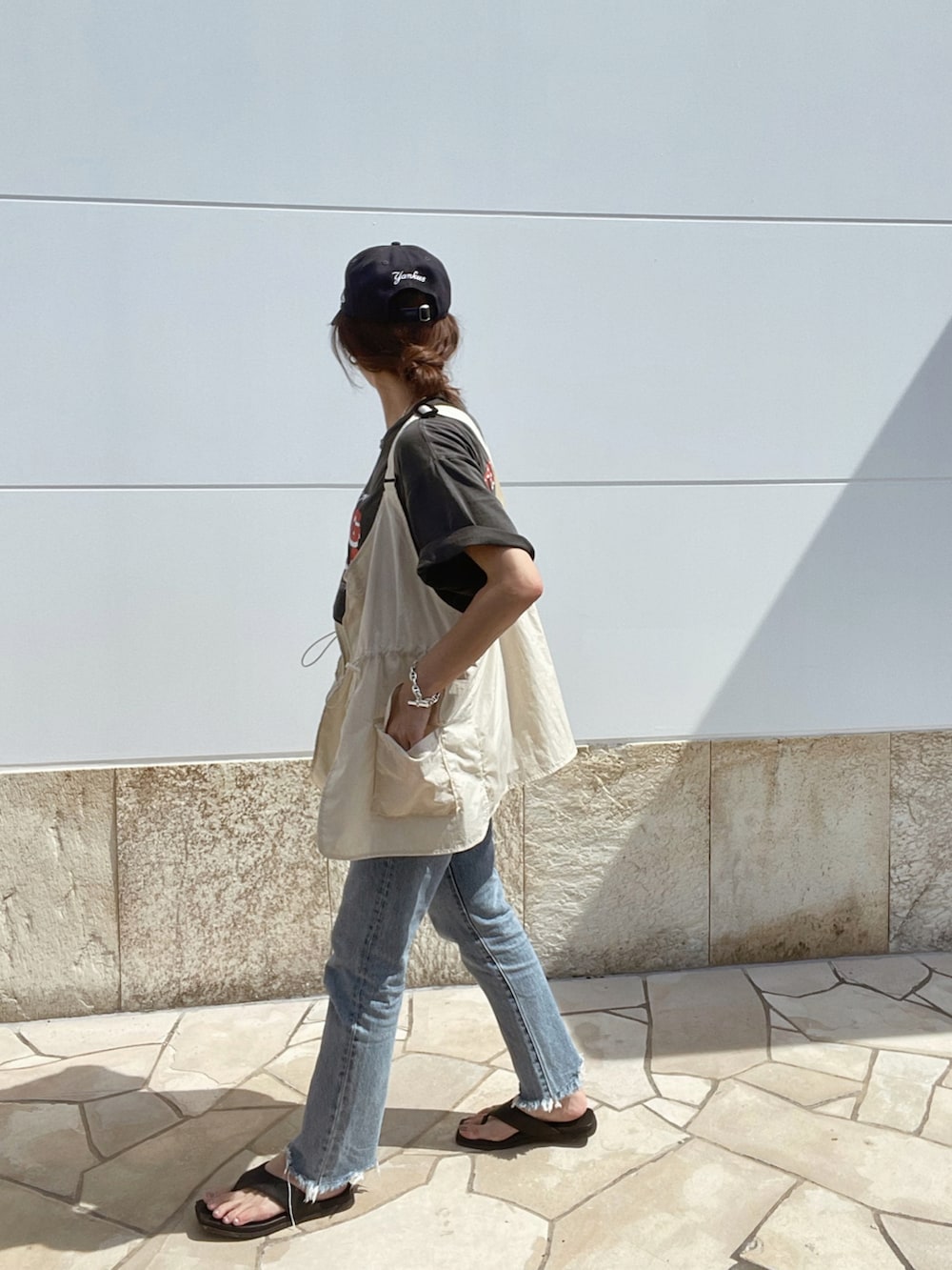 グレー系のTシャツ/カットソー、ブルー系のデニムパンツ、ベージュ系のベストを着用したレディースの夏コーディネートの2枚目の写真