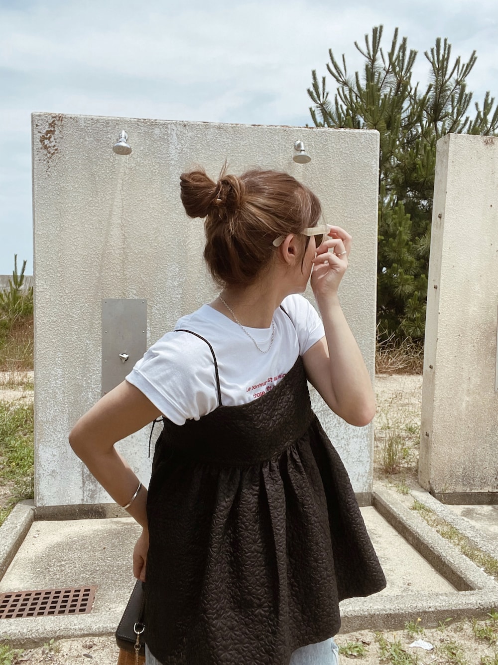 ブラック系のキャミソール、ブルー系のデニムパンツを着用したレディースの夏コーディネートの3枚目の写真