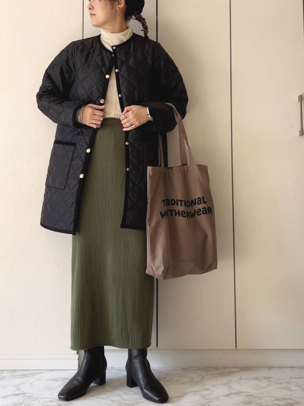 ブラック系のその他アウター、ホワイト系のTシャツ/カットソー、グリーン系のスカートを着用したレディースの冬コーディネートの2枚目の写真
