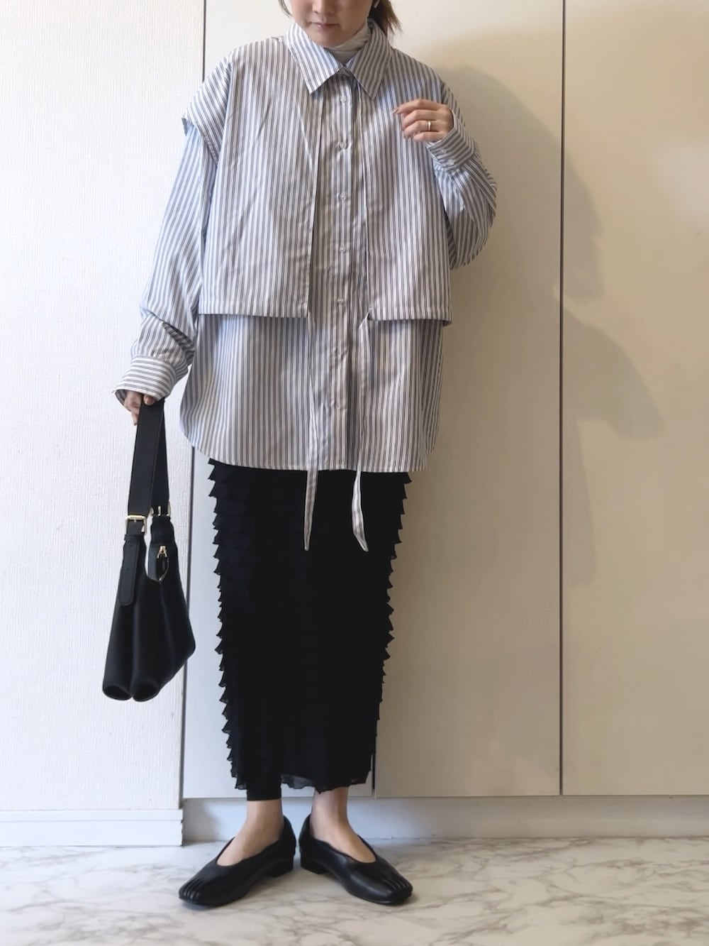 ホワイト系のシャツ/ブラウス、ブラック系のスカート、ブラック系のショルダーバッグを着用したレディースの春コーディネートの2枚目の写真
