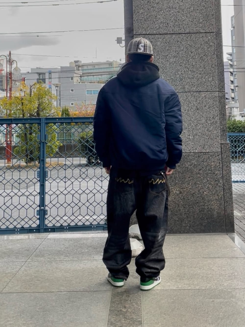 ブルー系のブルゾン、ブラック系のパーカー、ブラック系のデニムパンツを着用したメンズの春コーディネートの2枚目の写真