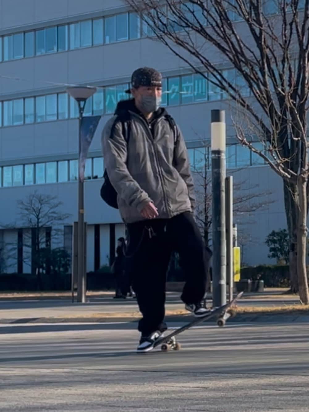 シルバー系のブルゾン、パープル系のスニーカー、ブラック系のパーカーを着用したメンズの冬コーディネートの3枚目の写真