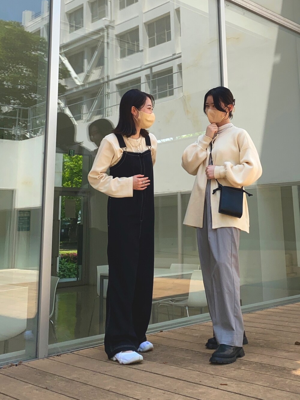 グレー系のスラックス、ホワイト系のカーディガン/ボレロ、ブラック系のショルダーバッグを着用したレディースの春コーディネートの2枚目の写真