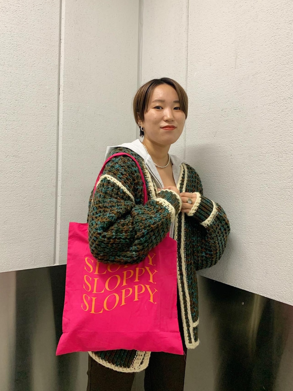 ベージュ系のパーカー、ブラック系のブーツ、ピンク系のトートバッグを着用したレディースの秋コーディネートの2枚目の写真