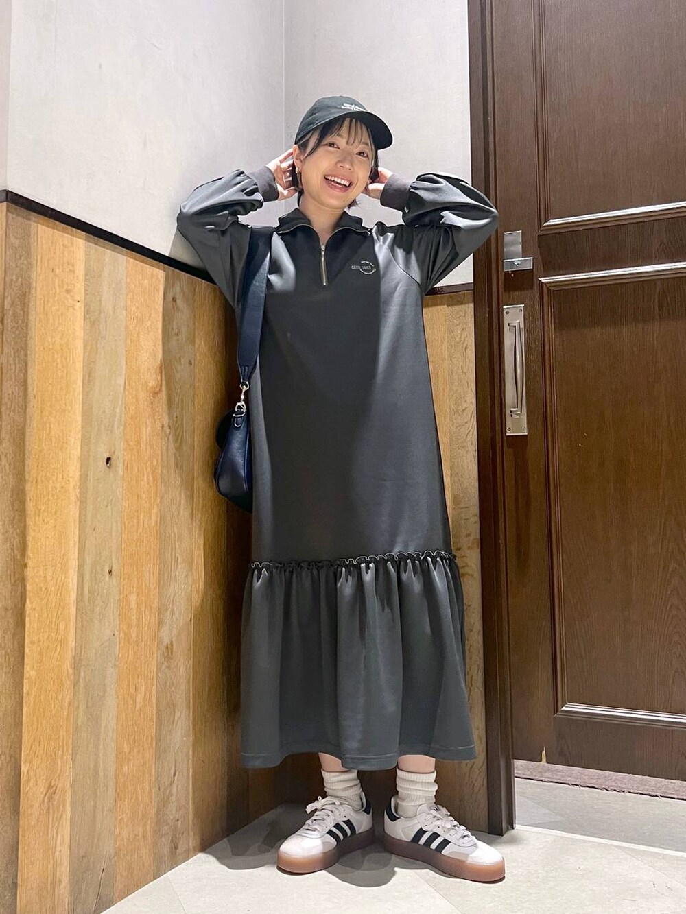 グレー系のワンピース、ホワイト系のスニーカー、ブルー系のショルダーバッグを着用したレディースの秋コーディネートの3枚目の写真