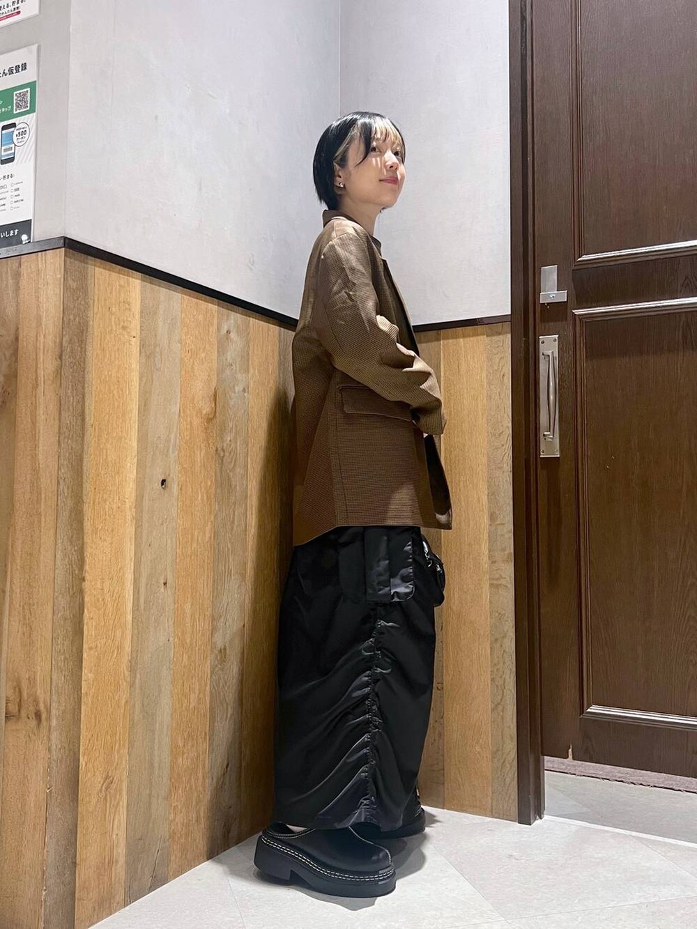 ブラック系のショルダーバッグ、ブラック系のスカート、ブラック系のローファーを着用したレディースの秋コーディネートの2枚目の写真