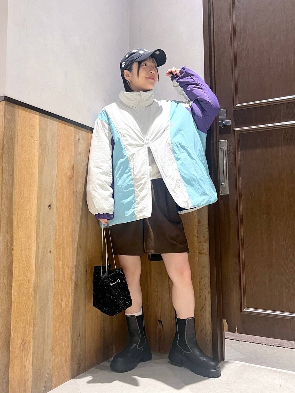 ホワイト系のダウンジャケット/コート、ブラック系のブーツ、ブラック系のハンドバッグを着用したレディースの秋コーディネートの2枚目の写真