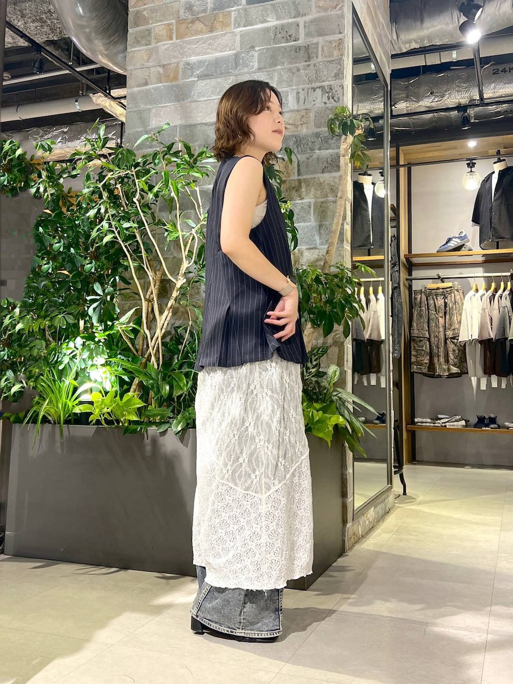 ホワイト系のタンクトップ、ブルー系のデニムパンツ、ブラック系のサンダルを着用したレディースの夏コーディネートの3枚目の写真