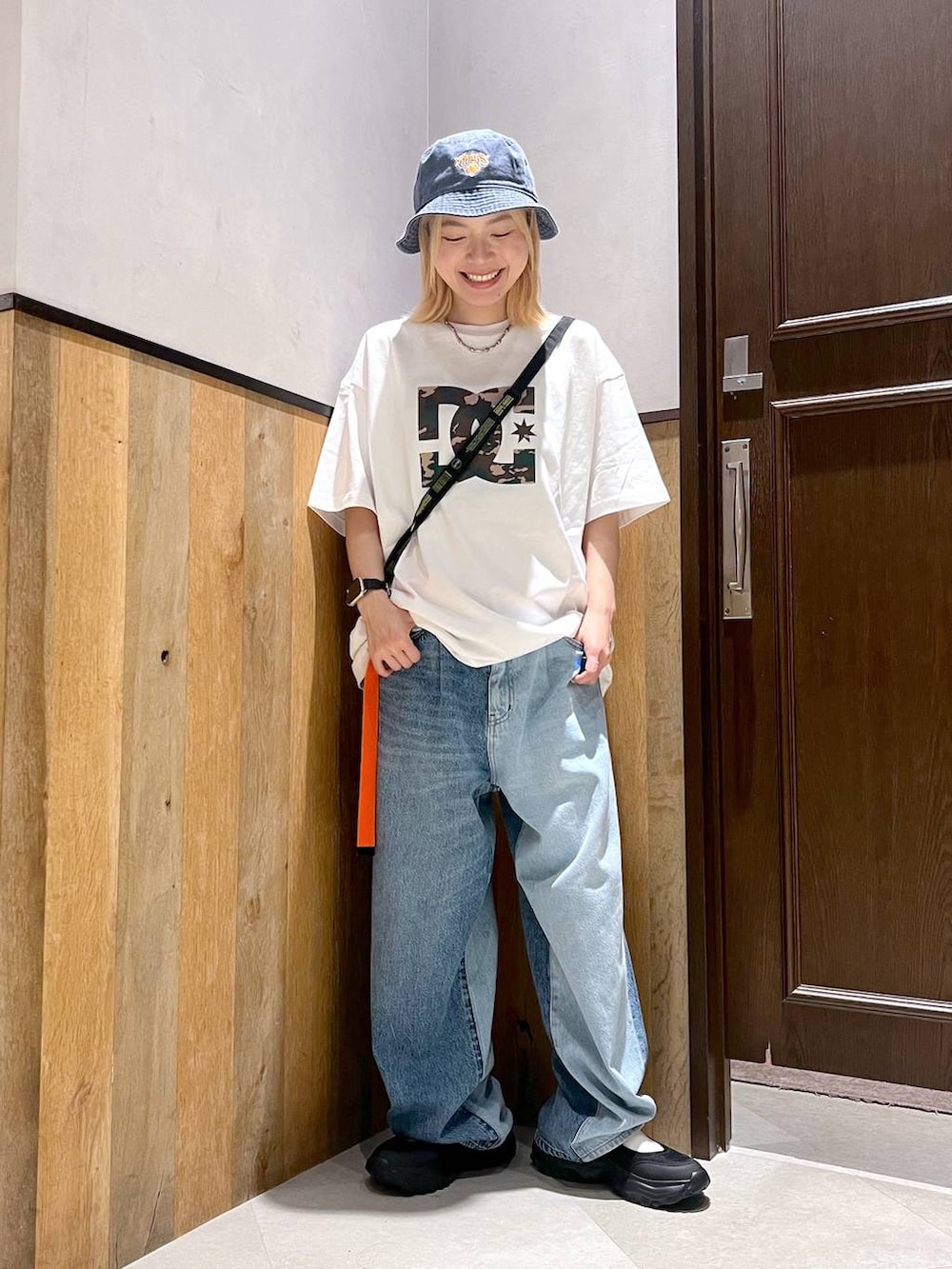 ブラック系のスニーカー、ブルー系のデニムパンツ、ブラック系のショルダーバッグを着用したレディースの秋コーディネートの4枚目の写真