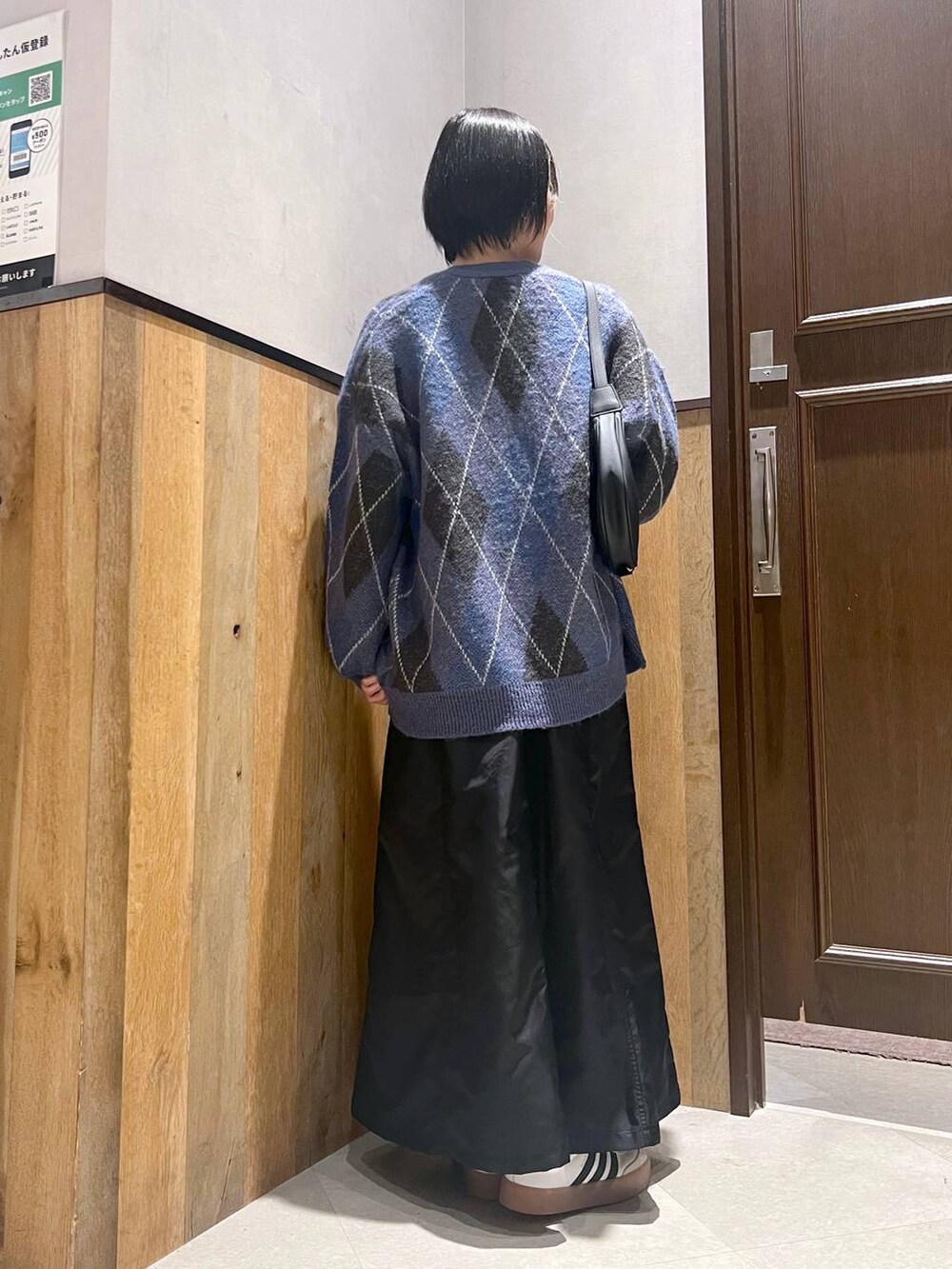 ブラック系のショルダーバッグ、ブルー系のカーディガン/ボレロ、ブラック系のジャンパースカートを着用したレディースの秋コーディネートの5枚目の写真