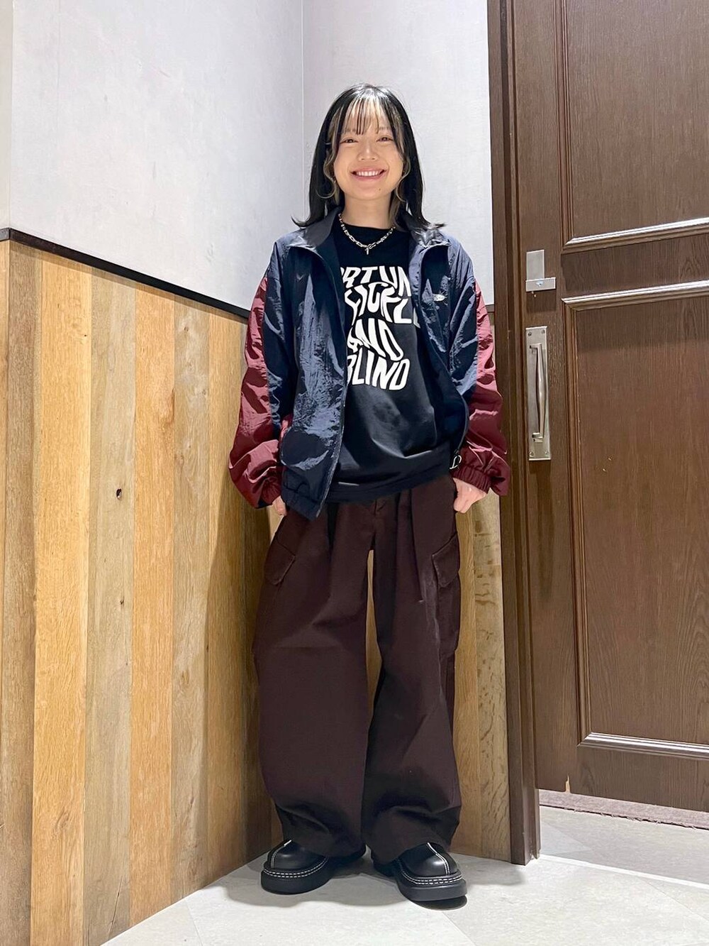 ブラウン系のカーゴパンツ、ブルー系のブルゾン、ブラック系のTシャツ/カットソーを着用したレディースの秋コーディネートの4枚目の写真