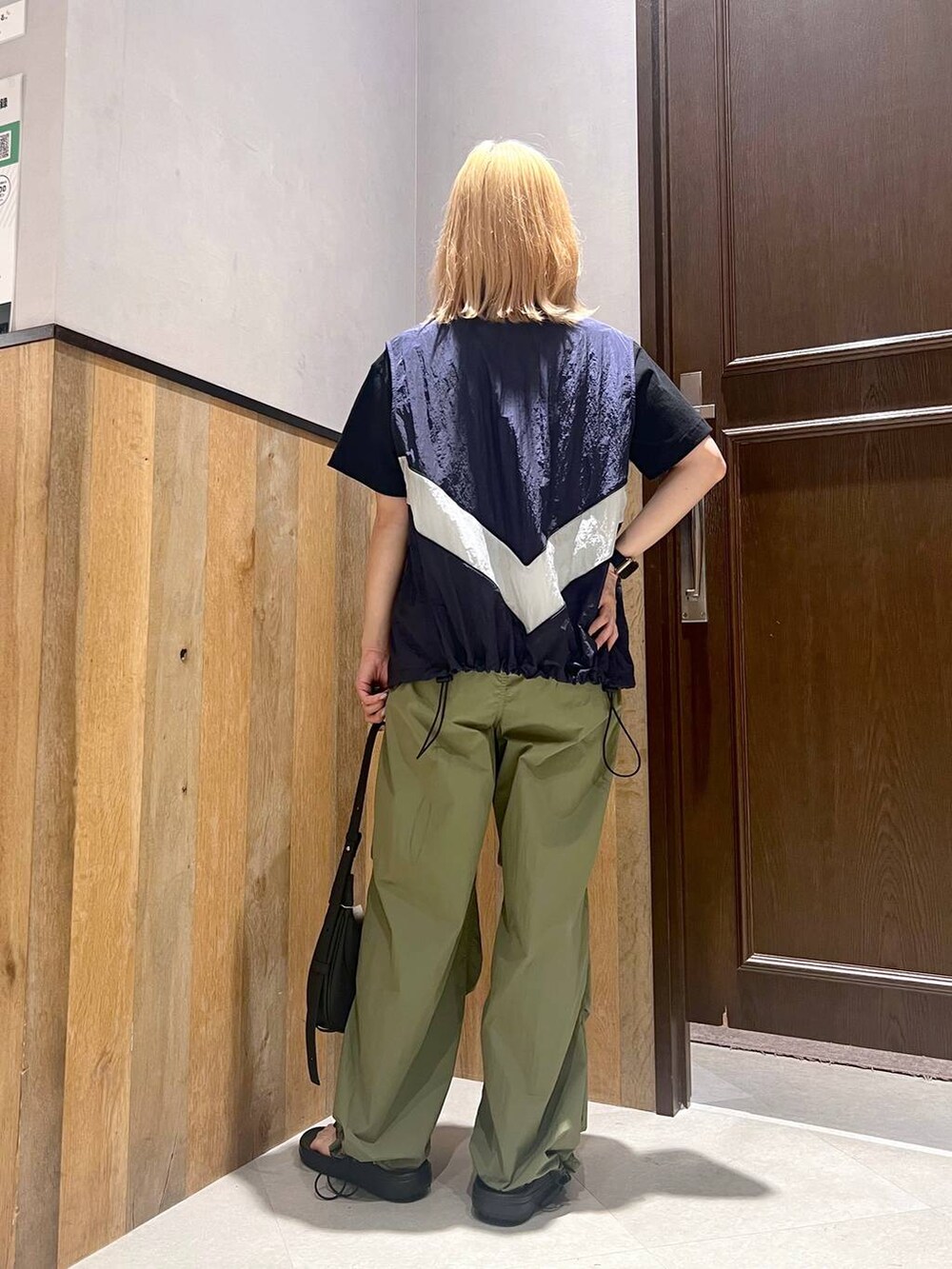 ブラック系のサンダル、ブルー系のベスト、グリーン系のカーゴパンツを着用したレディースの夏コーディネートの4枚目の写真