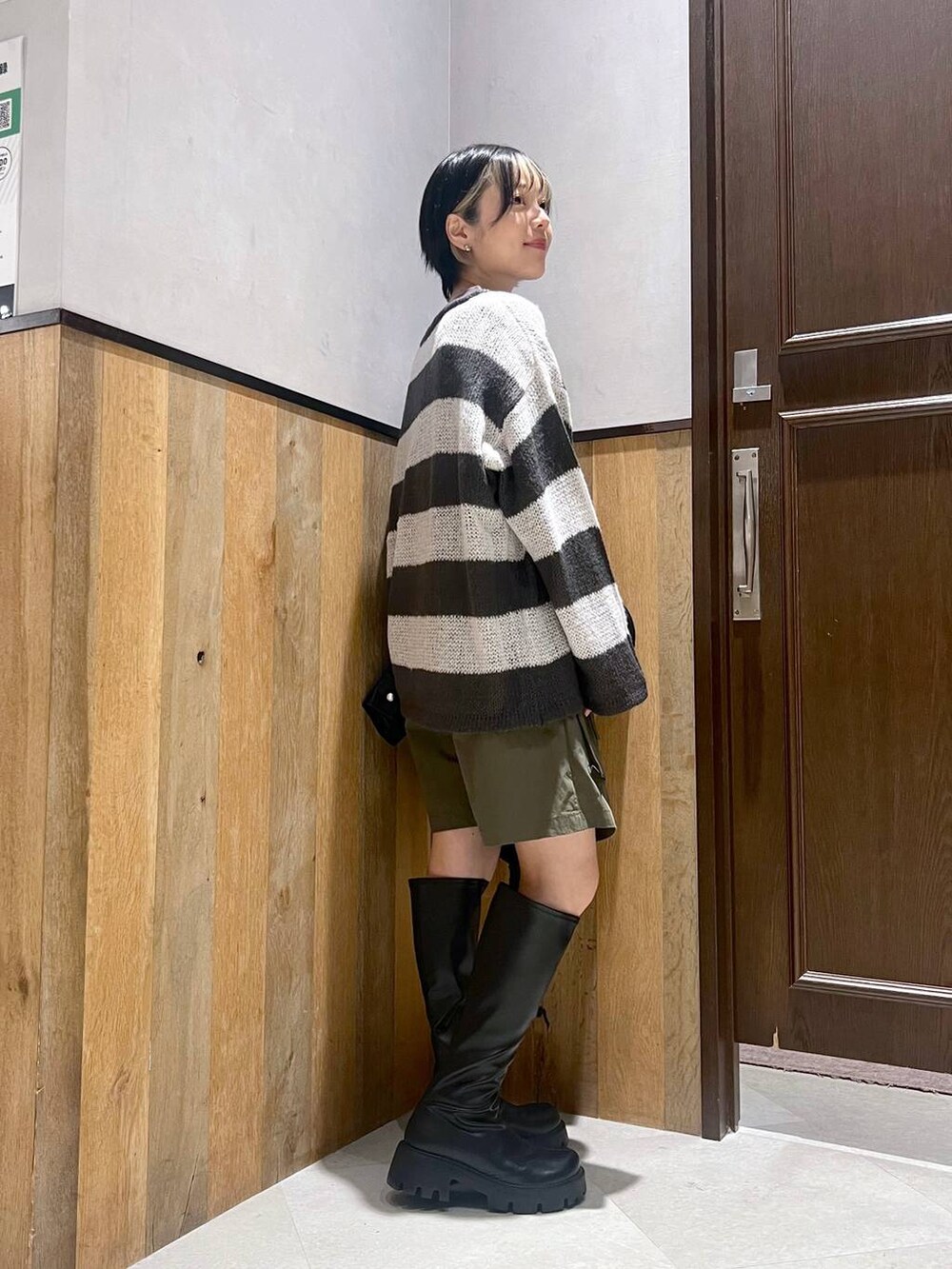 ブラック系のブーツ、ホワイト系のニット/セーター、ブラック系のブルゾンを着用したレディースの秋コーディネートの2枚目の写真