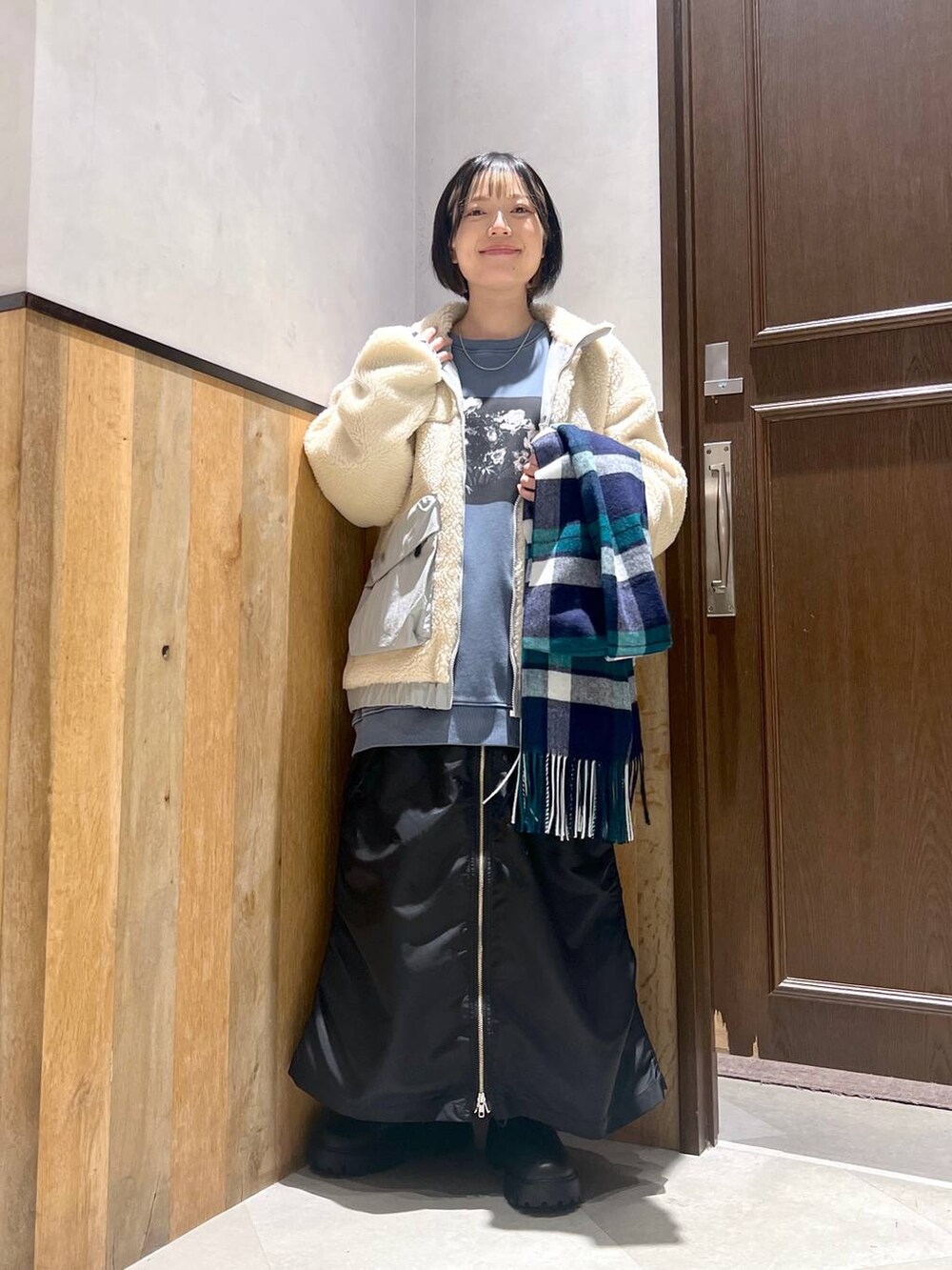 ホワイト系のブルゾン、ブラック系のブーツ、ブラック系のスカートを着用したレディースの秋コーディネートの4枚目の写真