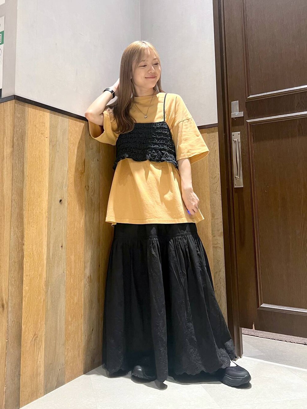 ブラック系のスニーカー、ブラック系のスカート、イエロー系のTシャツ/カットソーを着用したレディースの夏コーディネートの4枚目の写真