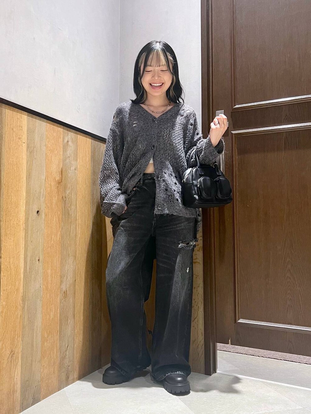 ブラック系のデニムパンツ、ブラック系のショルダーバッグ、ブラック系のブーツを着用したレディースの秋コーディネートの5枚目の写真