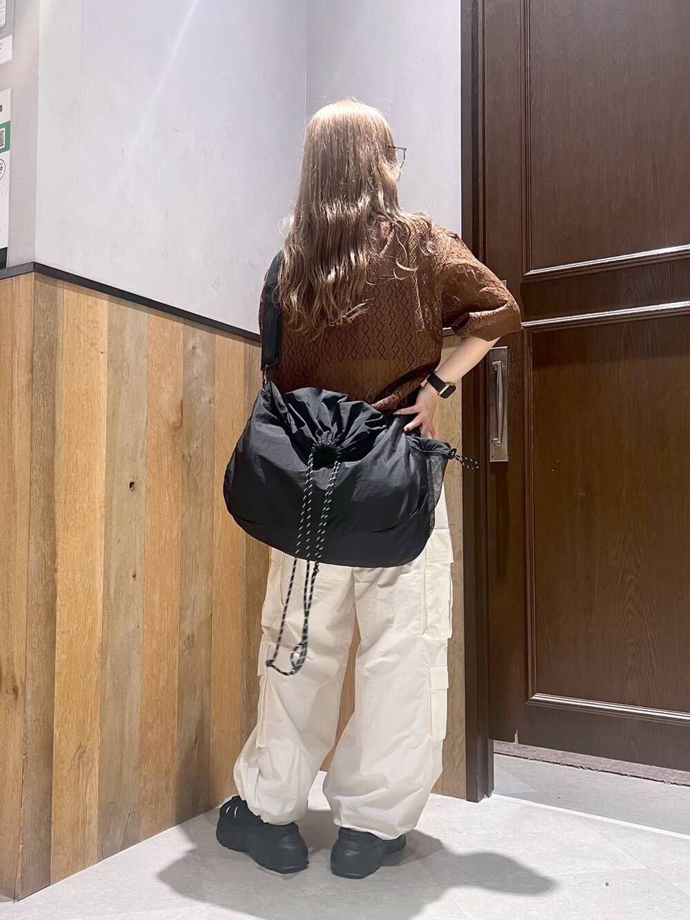 ブラウン系のポロシャツ、ホワイト系のカーゴパンツ、ブラック系のショルダーバッグを着用したレディースの夏コーディネートの3枚目の写真