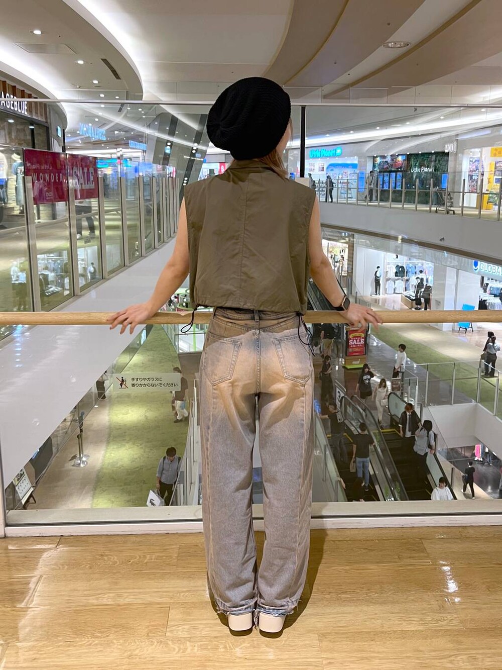 グリーン系のベスト、ホワイト系のキャミソール、ブルー系のデニムパンツを着用したレディースの夏コーディネートの2枚目の写真