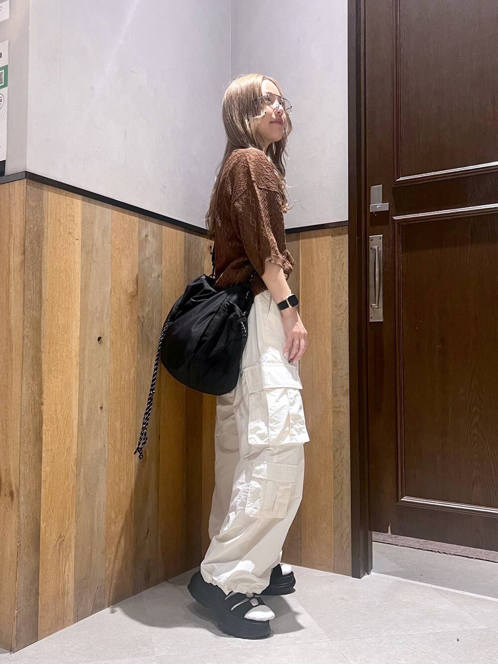 ブラウン系のポロシャツ、ホワイト系のカーゴパンツ、ブラック系のショルダーバッグを着用したレディースの夏コーディネートの2枚目の写真