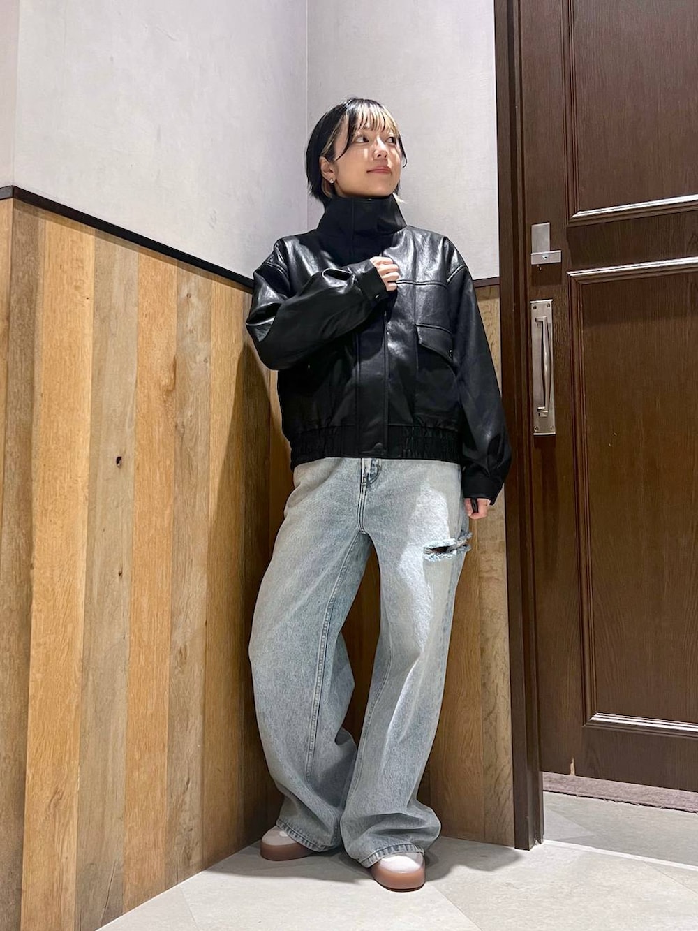 ブルー系のデニムパンツ、ブラック系のライダースジャケット、レッド系のTシャツ/カットソーを着用したレディースの秋コーディネートの5枚目の写真