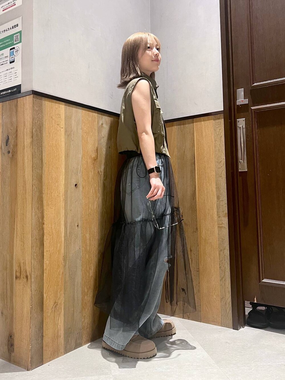 ブルー系のデニムパンツ、ブラック系のスカート、グリーン系のベストを着用したレディースの夏コーディネートの3枚目の写真