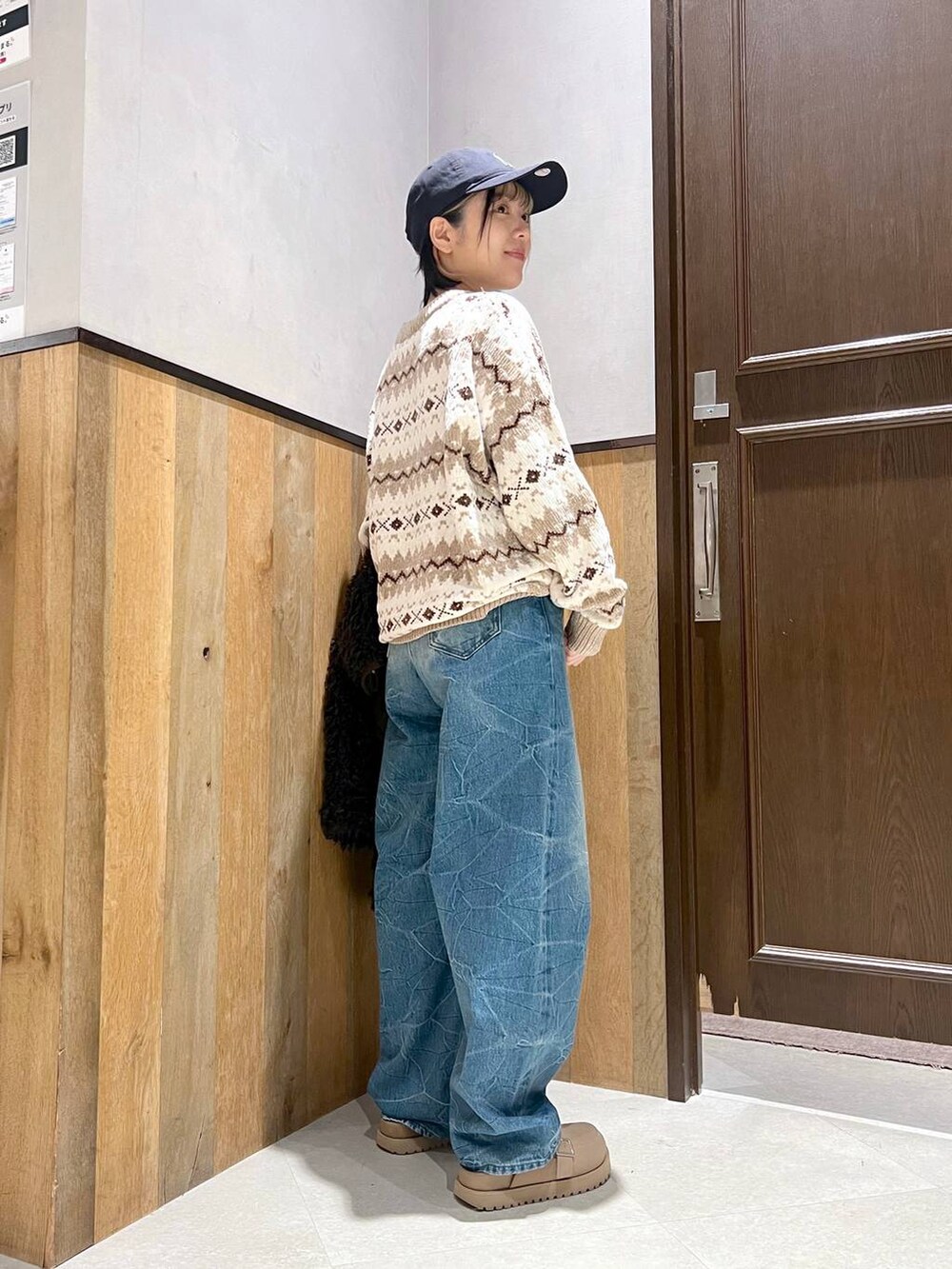 ホワイト系のニット/セーター、ブラウン系のブルゾン、ブルー系のデニムパンツを着用したレディースの秋コーディネートの3枚目の写真