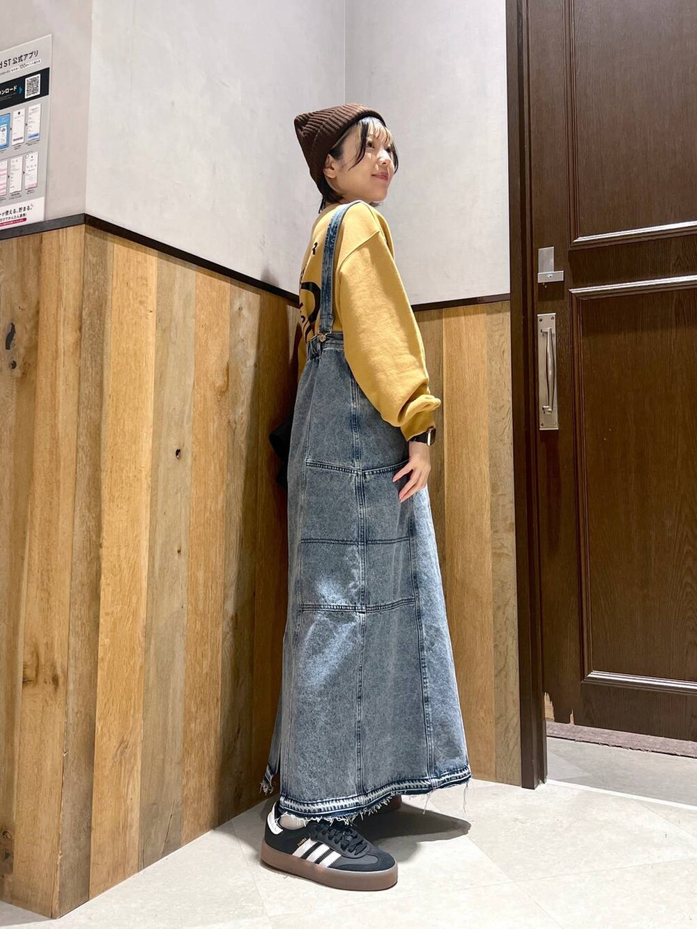 ブルー系のデニムスカート、ブラック系のブルゾン、イエロー系のスウェットを着用したレディースの秋コーディネートの2枚目の写真