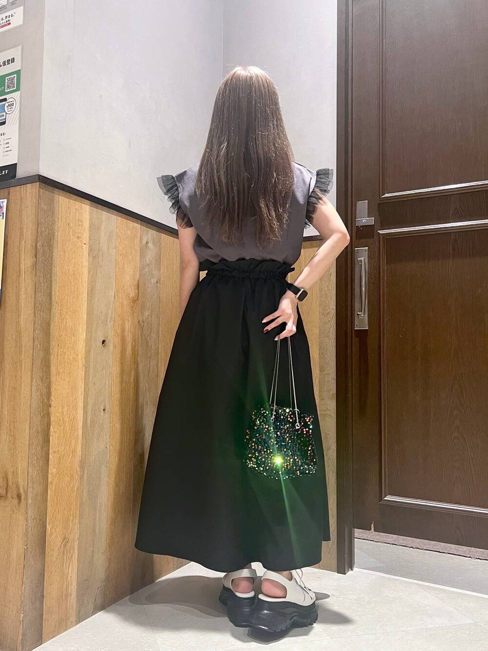 ブラック系のTシャツ/カットソー、ゴールド系のハンドバッグ、ブラック系のサンダルを着用したレディースの夏コーディネートの3枚目の写真