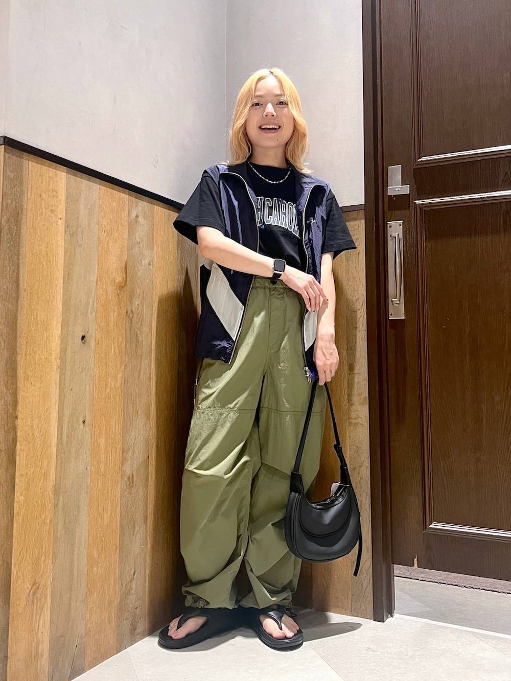 ブラック系のサンダル、ブルー系のベスト、グリーン系のカーゴパンツを着用したレディースの夏コーディネートの5枚目の写真