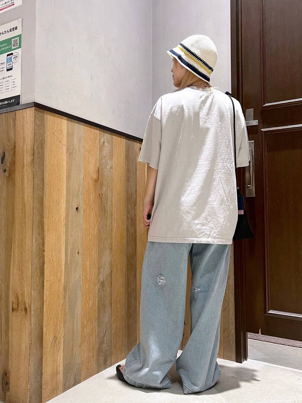 ブルー系のデニムパンツ、ブラック系のショルダーバッグ、ベージュ系のTシャツ/カットソーを着用したレディースの夏コーディネートの3枚目の写真