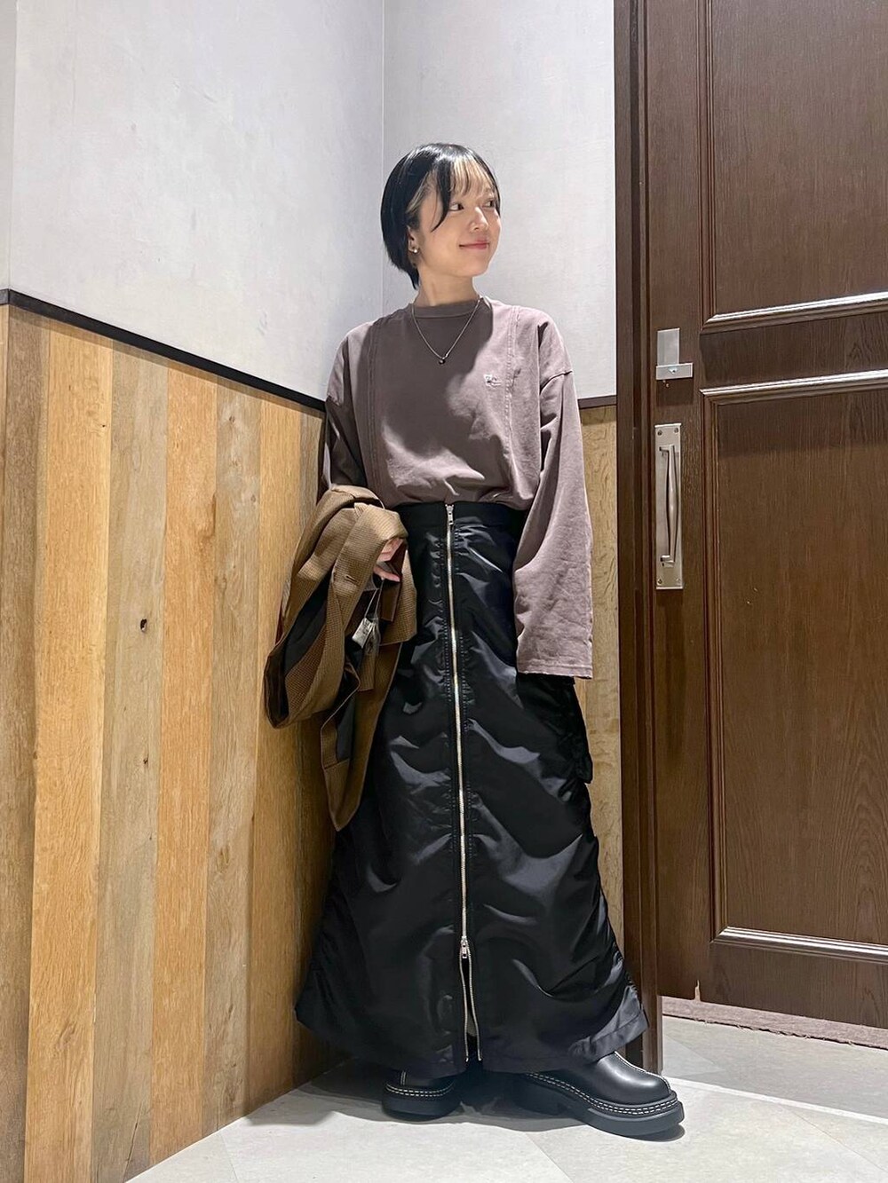 ブラック系のショルダーバッグ、ブラック系のスカート、ブラック系のローファーを着用したレディースの秋コーディネートの5枚目の写真