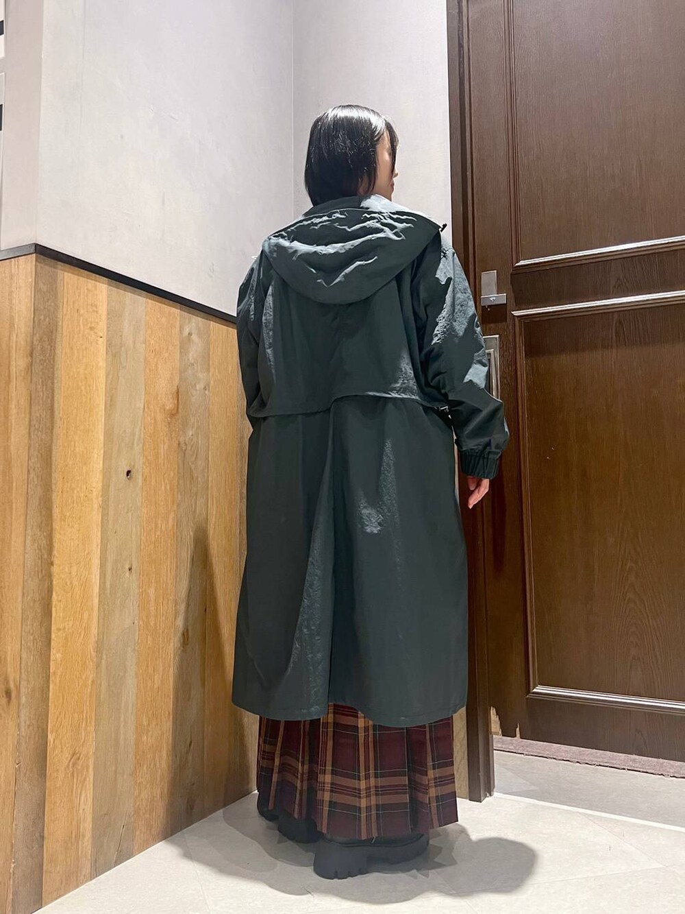 グリーン系のニット/セーター、ブラック系のブーツ、ブルー系のショルダーバッグを着用したレディースの秋コーディネートの6枚目の写真