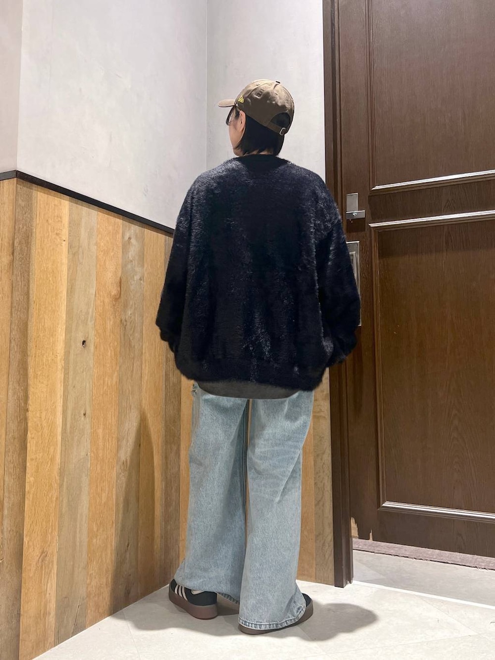 ブルー系のデニムパンツ、ブラック系のカーディガン/ボレロ、ブラック系のスウェットを着用したレディースの秋コーディネートの4枚目の写真